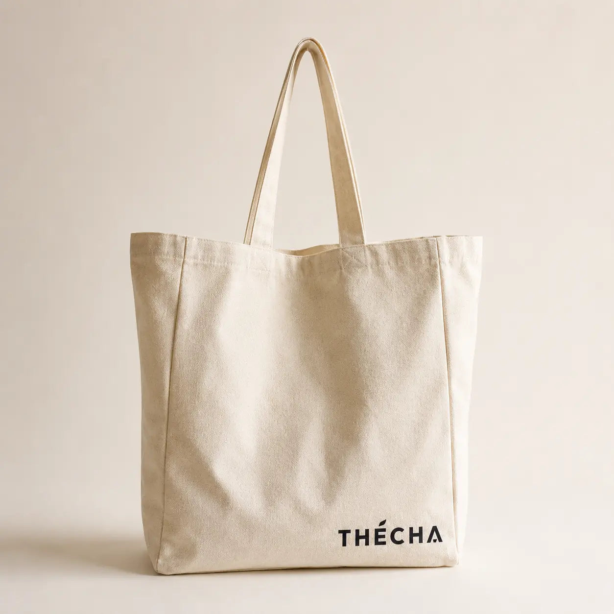 Tote bag en coton écru, format spacieux 33 × 34 × 10 cm, avec longues anses pour un porté épaule.